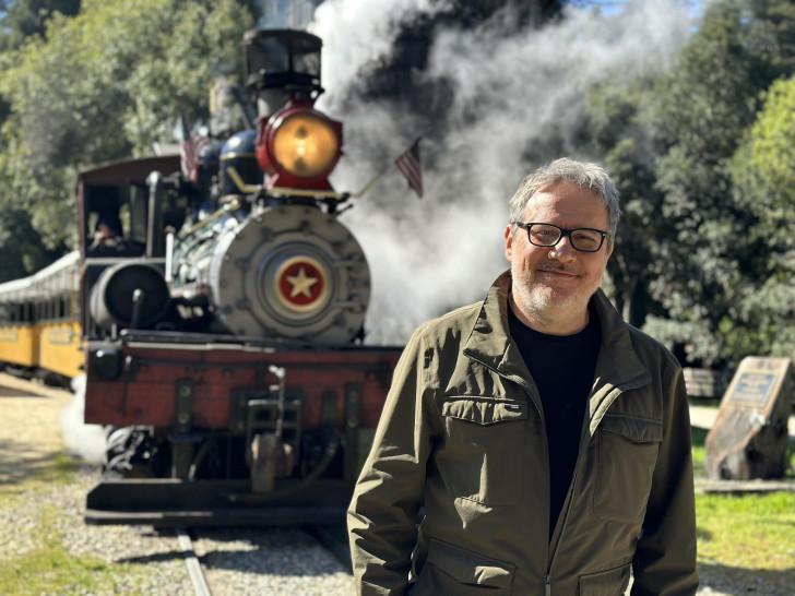 Philippe Gougler pose devant une locomotive à vapeur